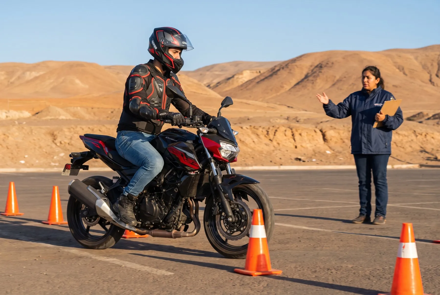 Alumno con casco integral y chaqueta de protección conduciendo una motocicleta entre conos, observado por su instructora