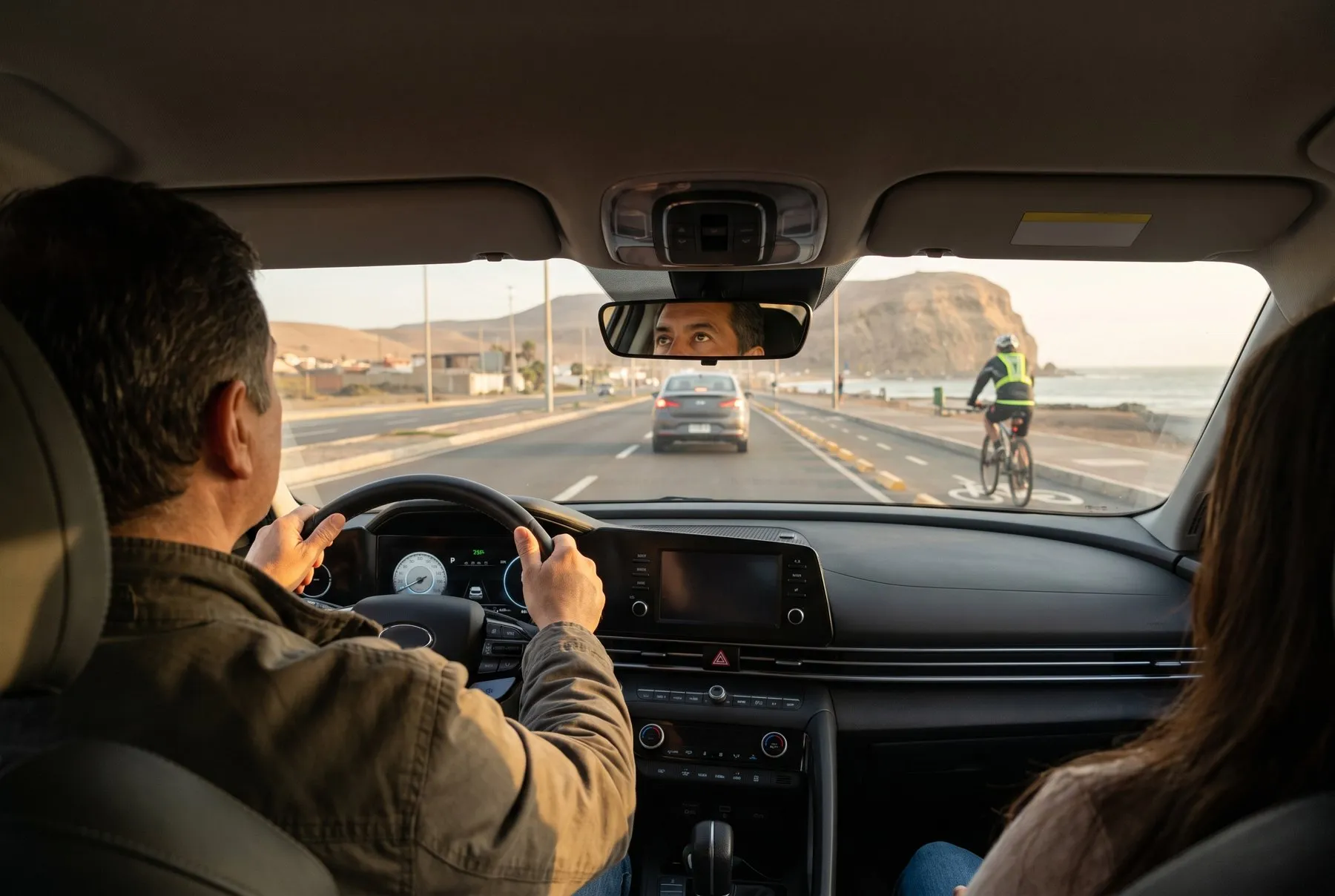 Conductor atento con ambas manos en el volante, manteniendo distancia en una avenida costera de Arica con el Morro al fondo